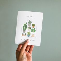 a hand holding up a card with potted plants on it and the words happy new home