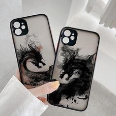 two phone cases with black and white designs on them, one is holding the other