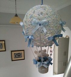 a teddy bear in a basket suspended from the ceiling with ribbons and bows on it