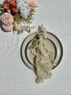 a white plate topped with a piece of cloth next to a bouquet of wildflowers