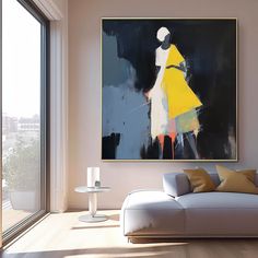 an abstract painting hangs on the wall above a couch in front of a large window