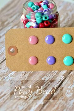 a jar filled with colorful beads sitting on top of a wooden table next to a tag