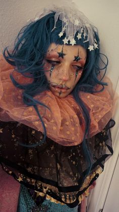 a creepy doll with blue hair wearing a veil and stars on it's head