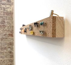 a wall mounted wooden earring holder on the side of a white wall next to a brick wall