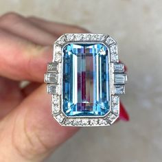 This beautiful ring features an approx 11.86-carat emerald-cut aquamarine bezel set within a handcrafted platinum mounting. The aquamarine is flanked by three baguette cut diamonds on each side and surrounded by a halo of round brilliant cut diamonds. Additional round brilliant cut diamonds are set along the shoulders. The total diamond weight is approx. 0.81 carats. This ring is decorated with fine milgrain and an openwork under-gallery. ✦ AQUAMARINE SPECIFICATIONS:    Aquamarine Cut: Emerald C Luxury Gia Certified Emerald Cut Gemstones, Luxury Topaz Ring Emerald Cut With Vvs Clarity, Luxury Emerald-cut Topaz Ring With Vvs Clarity, Luxury Gia-certified Emerald Cut Topaz Ring, Luxury Gia Certified Aquamarine Ring, Emerald Cut Platinum Gemstones For Gifts, Luxury Octagon Emerald Ring With Accent Stones, Luxury Aquamarine Octagon Ring, Gia Certified Emerald Cut Topaz Ring In Platinum