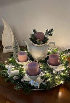 a tea pot filled with candles sitting on top of a table next to christmas decorations