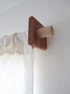 a wooden object hanging on the wall next to a white curtain with a brown handle