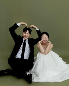 a man and woman sitting on the ground posing for a photo with their hands behind their heads