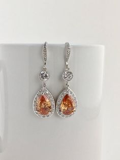 I've created these luxury morganite cubic zirconia bridal teardrop set rhodium plated brass setting. This set includes: # Luxury morganite cubic zirconia bridal teardrop earrings in rhodium plated brass setting. Earrings feature a large teardrop with pear cut morganite cubic zirconia center surrounded by tiny round zirconia crystals. Teardrop dangles from a round cubic zirconia connector and zirconia detailed ear wire. Total length of the earrings is 5 cms. # Luxury morganite cubic zirconia brid Orange Teardrop Anniversary Jewelry, Elegant Pear-shaped Orange Jewelry, Orange Teardrop Jewelry For Wedding, Elegant Orange Pear-shaped Jewelry, Orange Drop Earrings For Wedding, Orange Cubic Zirconia Jewelry For Anniversary, Elegant Orange Jewelry For Wedding, Elegant Orange Wedding Jewelry, Elegant Peach Earrings For Wedding