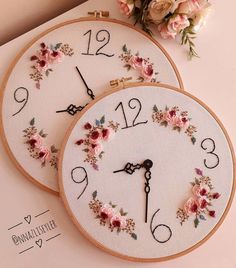 two embroidered clocks with flowers on them sitting next to each other