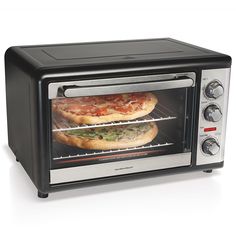 two pizzas are being cooked in an open toaster oven on a white surface