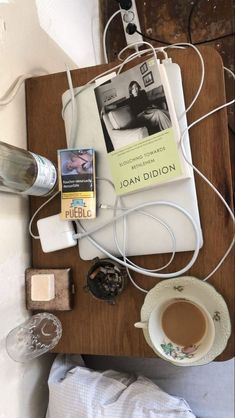 a wooden table topped with an electronic device next to a cup of coffee and other items