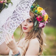 a woman holding an umbrella with flowers in her hair and wearing a flower crown on her head