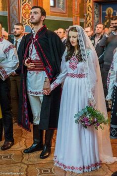 a man and woman dressed in traditional clothing standing next to each other at a wedding