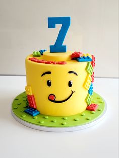 a yellow birthday cake with the number seven on it's face and legos