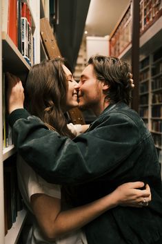 a man and woman are kissing in front of bookshelves at the same time