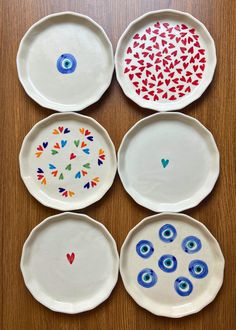 four plates with different designs on them sitting on top of a wooden table next to each other