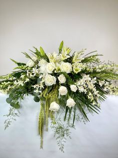 a bouquet of white flowers and greenery on a table