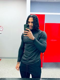 a man with dreadlocks is taking a selfie in the bathroom while holding his cell phone