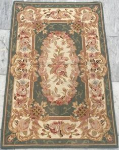 the rug is laying on the floor next to it's tile border, which has pink flowers and green leaves