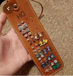 a hand holding a brown case with lots of pins on it