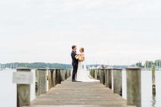 a bride and groom standing on a pier