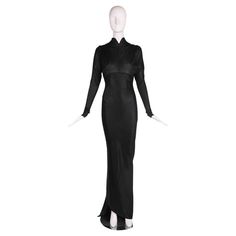 1986 F/W Azzedine Alaia black acetate knit floor-length evening gown with stand collar, vertical gathers at the bust that create a unique shoulder detail and an open back in the shape of a deep V to the waistline. The fabric is cut on the bias and punctuated with diagonal seaming from front to back which forms an asymmetric train at the hem. There is a built-in body suit at the interior with a snap closure. Size tag M, 100% acetate. In excellent condition. Please consult measurements. Shoulders: Evening Gown With Long Train, Fitted Full Length Evening Dress For Dinner, Fitted Bias Cut Maxi Dress For Dinner, Black Fitted Gown For Dinner, Fitted Maxi Length Gown For Dinner, Fitted Maxi Dress With Sweep Train For Evening, Fitted Evening Gown For Dinner, Fitted Floor-length Gown For Dinner, Fitted Floor-length Dinner Gown