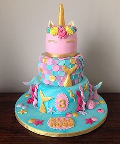 a birthday cake decorated with pink, blue and yellow icing is sitting on a wooden table