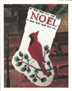 a cross stitch christmas stocking with a cardinal on it, hanging from a tree