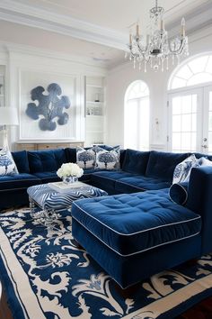 a living room filled with furniture and a chandelier hanging from the ceiling over a blue rug