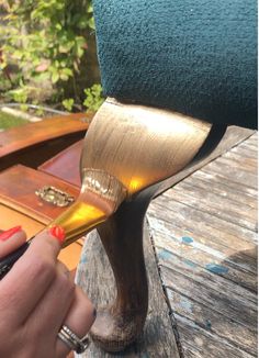 a close up of a person using a brush to paint a piece of wood on a table