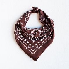 a brown bandana with white stars and swirls on it, against a white background