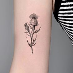 a black and white photo of a flower on the back of a woman's arm