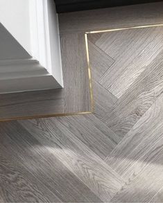 an image of wood flooring with white and gold trim on the bottom half of it