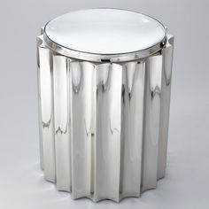 a round glass table with metal legs and a white top on a grey background in the style of art deco