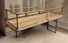 a wooden bench sitting in front of a glass case on top of a metal frame