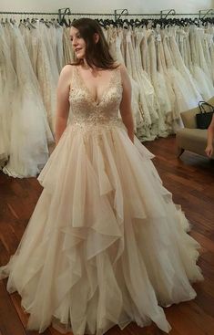 a woman standing in front of a rack of wedding dresses