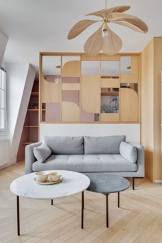 a living room filled with furniture next to a wooden wall mounted ceiling fan on top of a hard wood floor