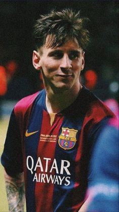 a man with tattoos on his face and chest standing in front of a soccer ball