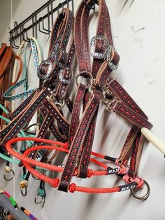 several different colored leather bridles hanging on a wall