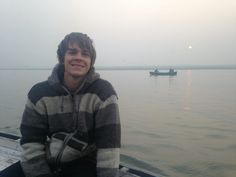 a young man sitting on top of a boat in the water