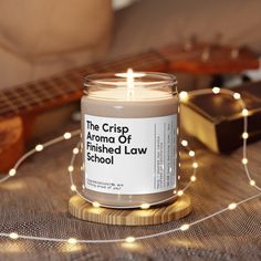 the crisp aroma of finished law school candle sits on a table next to a guitar