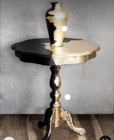 a table with a vase sitting on top of it next to a white and black wall