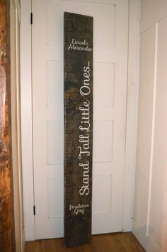 a tall wooden sign sitting on top of a hard wood floor next to a white door