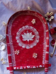 a red wicker tray with white flowers and leaves on it, next to other items