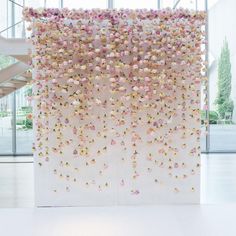 a white wall with pink and yellow flowers hanging from it's sides in front of a staircase