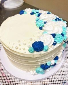 a large white cake with blue and white flowers on it's side sitting on a table