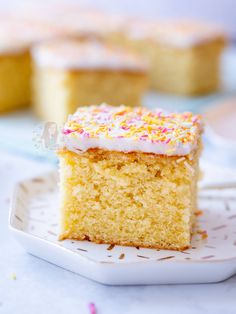 a piece of cake with white frosting and sprinkles on a plate