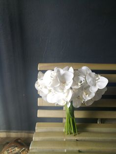 a bouquet of white flowers sitting on top of a wooden bench