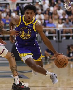 a basketball player dribbles the ball while being guarded by another player on the court